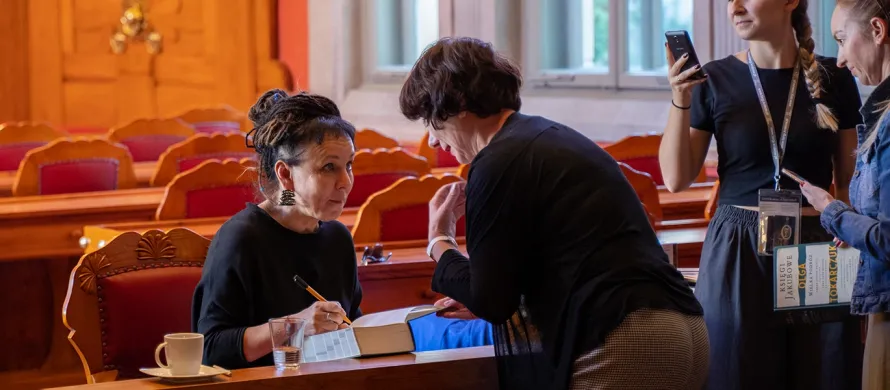 A professional chauffeur holding a door open for a writer on an Author Book Signing Tour across the UK.