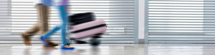 A luxury chauffeur-driven vehicle parked at a UK airport terminal, ready for passengers holidaying abroad to start their journey in comfort.