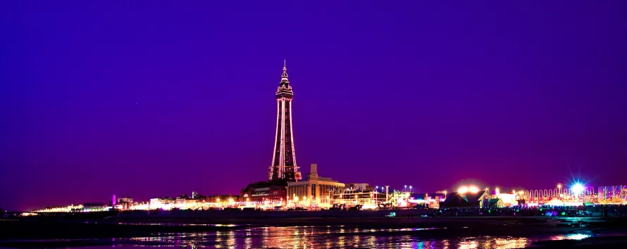 Luxury Mercedes V-Class chauffeur car parked near the Blackpool Illuminations light display on the promenade.