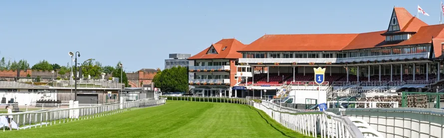 A luxury silver Mercedes-Benz V-Class chauffeur car parked outside Chester Racecourse for guests attending the Chester Races Summer Saturday event.