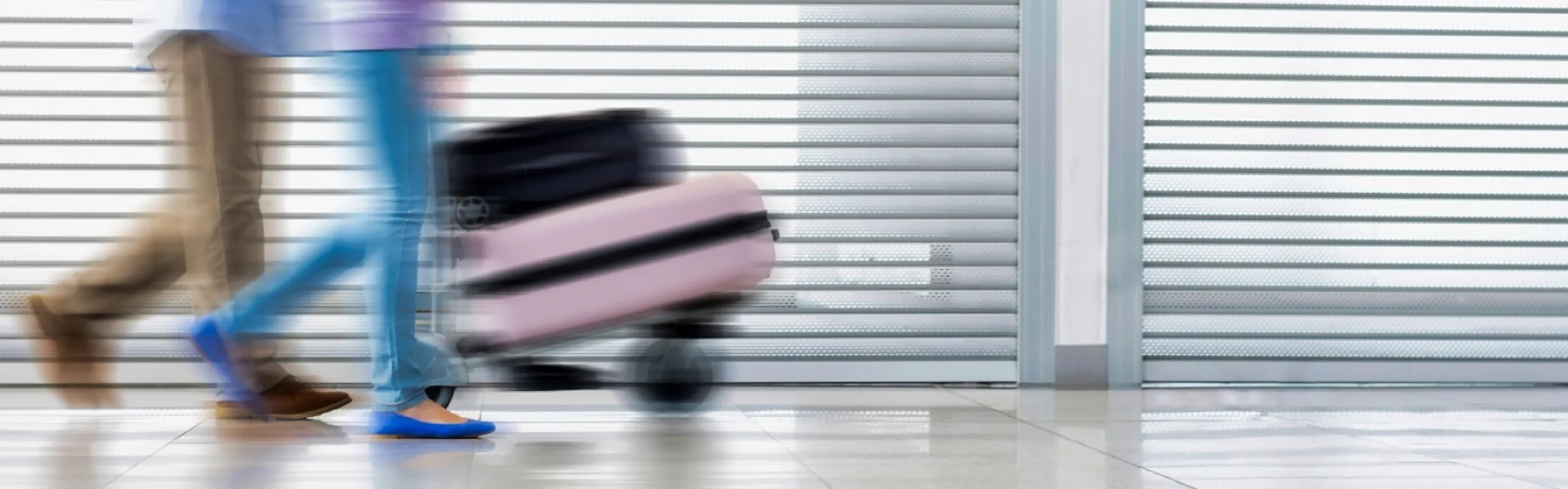 A luxury chauffeur-driven vehicle parked at a UK airport terminal, ready for passengers holidaying abroad to start their journey in comfort.